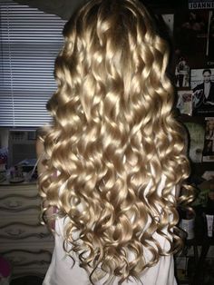 the back of a woman's head with long, curly blonde hair in it