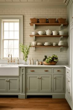 a kitchen with green painted cabinets and white counter tops, open shelving above the sink