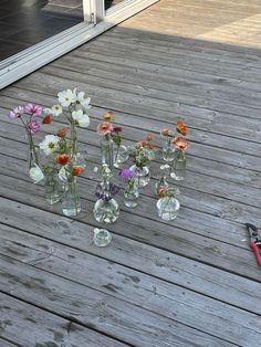 flowers in vases sitting on a wooden deck