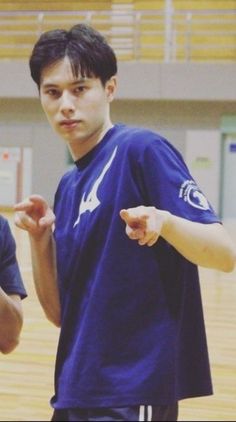 two young men standing next to each other on a basketball court with one pointing at the ball