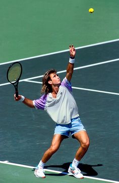 a man holding a tennis racquet on top of a tennis court with a ball in the air