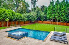 a backyard with a swimming pool and lounge chairs