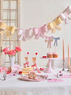 a table topped with cake and cupcakes on top of a white table cloth