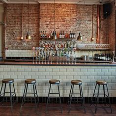 the bar has four stools and several bottles on it