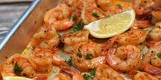 a pan filled with shrimp and lemon on top of a wooden table