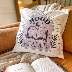 an open book sitting on top of a couch next to a pillow that reads noodle reader