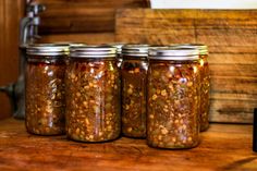 four jars filled with food sitting on top of a wooden table