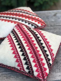 two red and black decorative pillows sitting on top of a wooden table