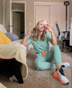 a woman sitting on the floor taking a selfie with her cell phone in front of her