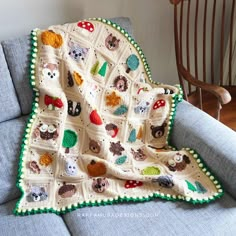 a crocheted blanket with animals on it sitting on a blue couch next to a rocking chair