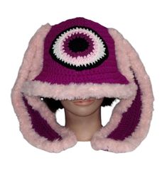 a knitted hat with an eyeball on the front and pink fur around the brim