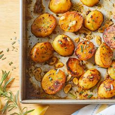 roasted potatoes and mushrooms on a baking sheet with rosemary sprigs next to them