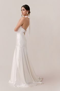 a woman in a white wedding dress is standing back to back with her hand on her shoulder