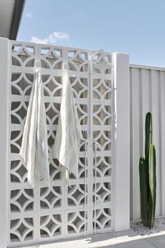 two towels are hanging on the side of a white fence next to a cacti