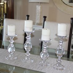 three clear candles are sitting on a glass table with two white candles in the middle