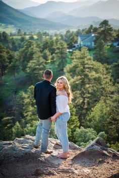 a man and woman standing on top of a mountain