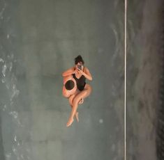 two women in swimsuits are floating on the water and one is holding a cell phone