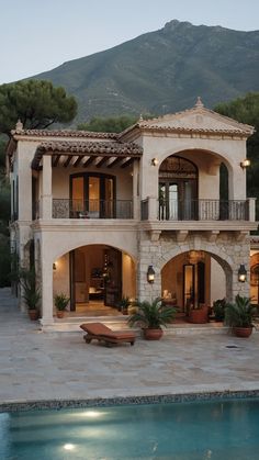 a large house with a pool in front of it and mountains in the back ground