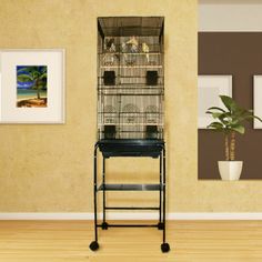 a bird cage sitting on top of a wooden floor next to a potted plant