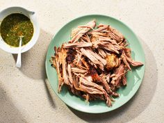 a green plate topped with meat next to a bowl of sauce