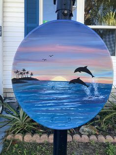 a blue and white painted sign with a dolphin jumping out of the water in front of a house