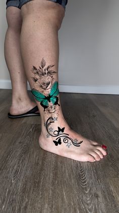 a woman's foot with a butterfly and flower tattoo on the side of her leg