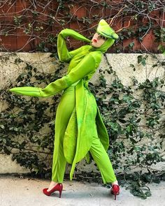 a woman dressed in green is walking down the street