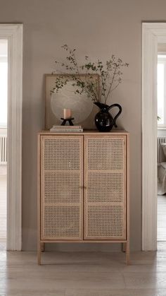 a white vase sitting on top of a wooden cabinet