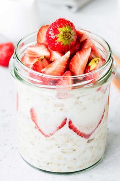 a glass jar filled with yogurt and strawberries on top of a table