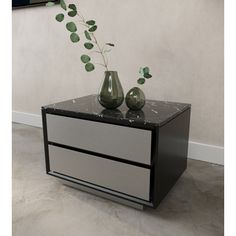 two green vases sitting on top of a black and white dresser next to a plant