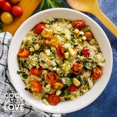 a white bowl filled with rice, tomatoes and broccoli next to a wooden spoon