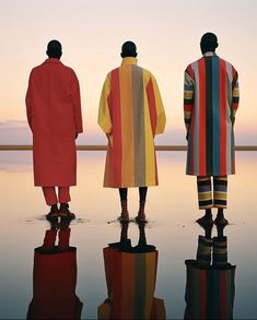 three men standing in front of a body of water with their backs to the camera