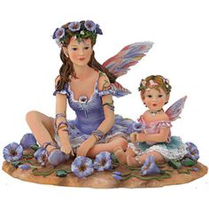 a figurine of a mother and child sitting on the ground with flowers in their hair