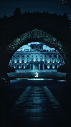 a building lit up at night with lights on it's side and an archway leading to the entrance