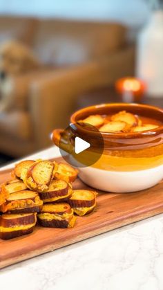 a wooden cutting board topped with slices of bread next to a bowl of sliced potatoes