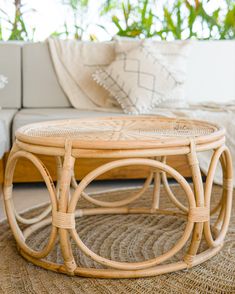 a wicker coffee table sitting on top of a rug in front of a couch