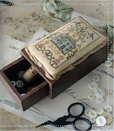 an old sewing box with some buttons in it and a pair of scissors next to it