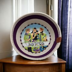 a crocheted plate with the words sisters on it sitting on a wooden table