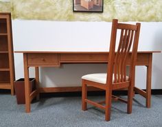 a wooden desk with a chair next to it and a bookcase on the wall