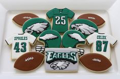 decorated cookies in the shape of footballs and jerseys are arranged on a white platter