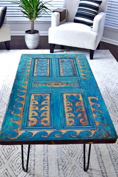 a coffee table that has been painted with blue and gold designs on it in a living room