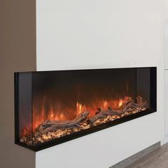 an electric fireplace with logs on the side and fire flames in the middle, next to a white wall