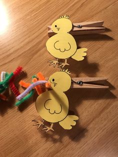 three wooden pegs with cut out chickens and carrots attached to them on a table