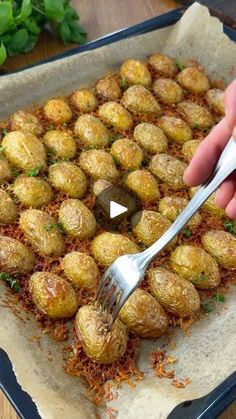 a person is holding a fork over some food on a baking sheet with parmesan sprinkles