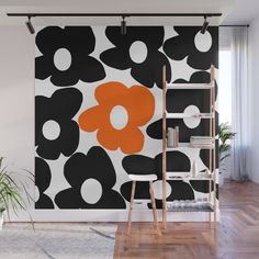 an orange flower on black and white wall mural in a living room with wooden flooring