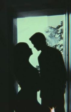 the silhouette of two people standing next to each other in front of an open window