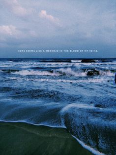 the ocean with waves coming in to shore and an overcast sky above it that reads, more swim like mermaid in the blood of my mind