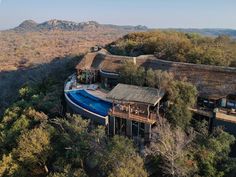 an aerial view of a house with a pool in the foreground and mountains in the background