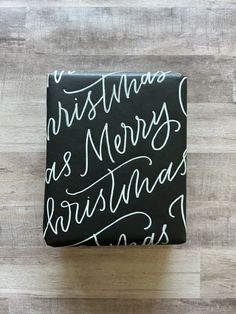 a gift wrapped in black paper decorated with white merry christmas writing Christmas Calligraphy Cards, Christmas Lettering Ideas, Bible Verse Lettering, Calligraphy Christmas Cards, Pen Lettering, Pretty Writing, Hand Lettering Styles, Brush Pen Lettering