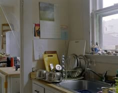 the kitchen is cluttered with dishes and utensils on the counter, near a window